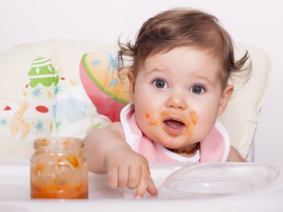 An adorable smudgy female baby eating her favorite food